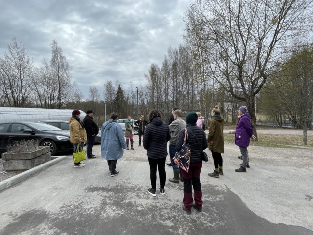 Ihmisiä (selkäpuolelta) pihalla harvahkossa ringissä