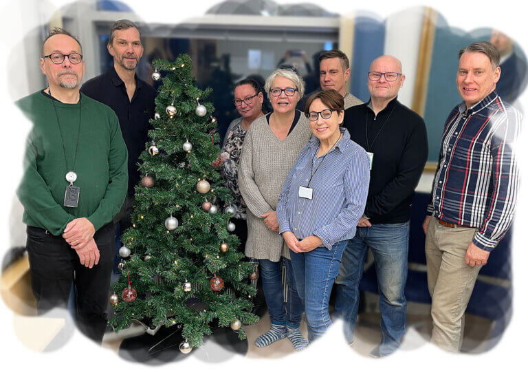 Kuvassa on joukko ihmisiä seisomassa joulukuusen ympärillä.