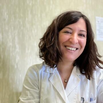 Nuori nainen hymyilee valkoisessa lääkärin takissa.