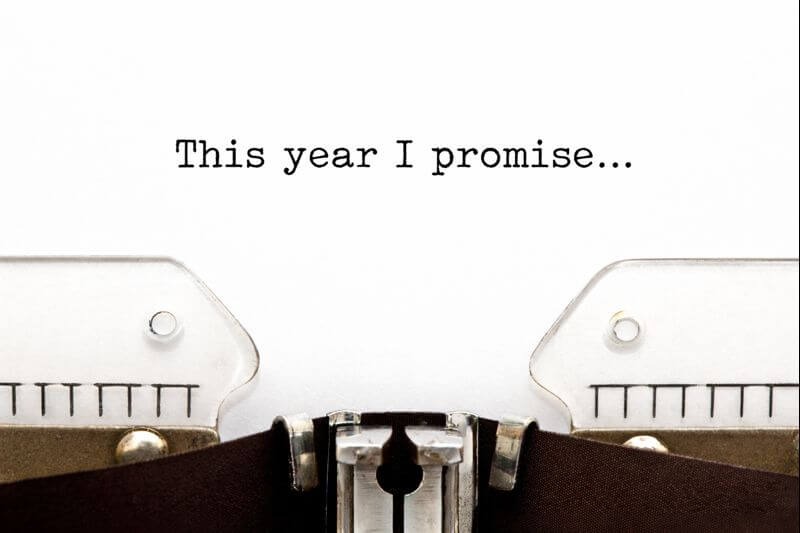 A close-up of a typewriter showing a sheet of paper with the text "This year I promise..." typed on it.