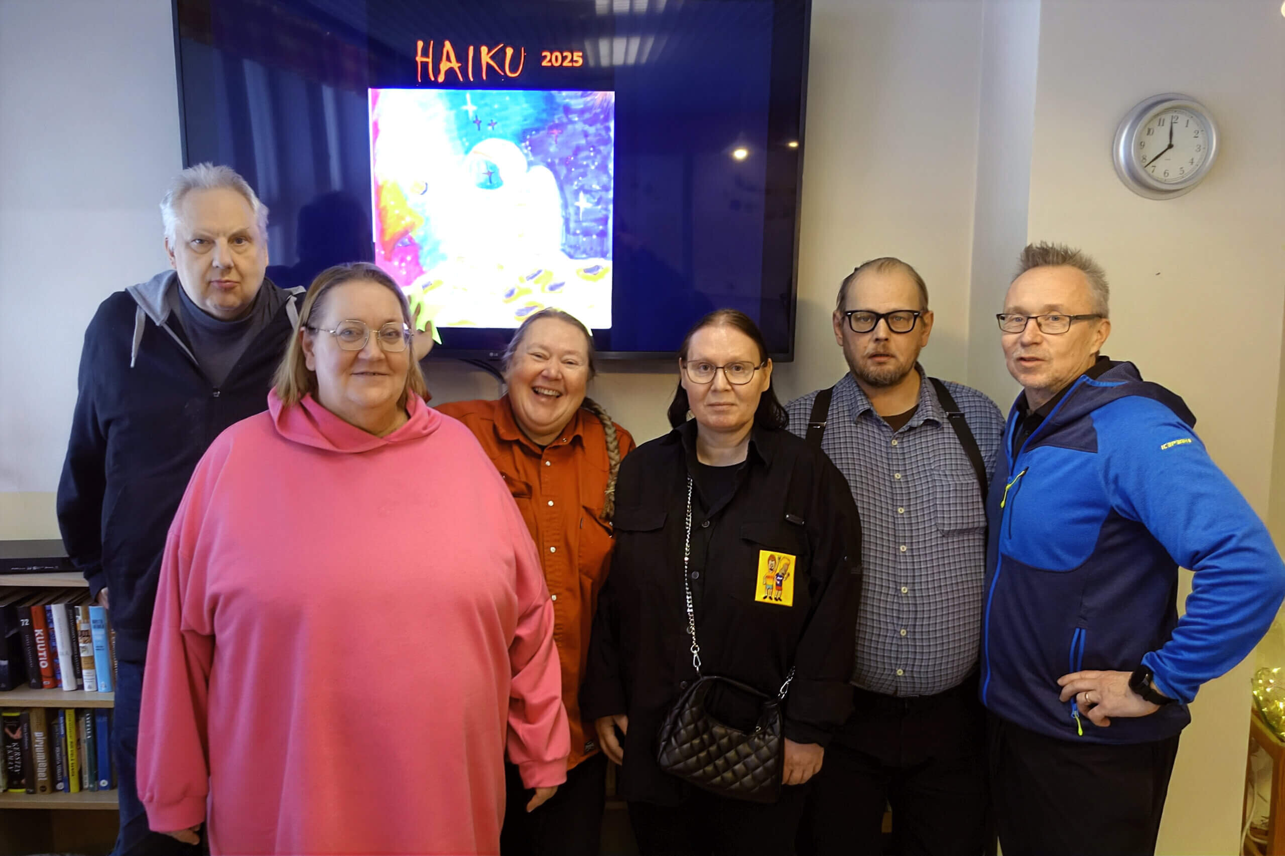 Kuudesta henkilöstä koostuva ryhmä seisoo yhdessä taustalla näkyvän 