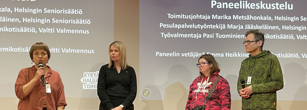 Paneelikeskustelussa esiintyy neljä henkilöä, joista yksi puhuu mikrofoniin ja taustalla näkyy esitystekstiä.