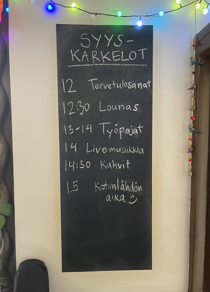 Taululla on ohjelma syysjuhlaan, jossa on aikataulu tervetulotoivotuksista, lounaasta, työpajoista, livemusiikista, kahveista ja kotiinlähtöajasta.